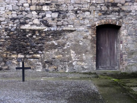 A small cross stands on the spot where the men stood before the firing squads, beside the door through which their dead bodies would be carried.